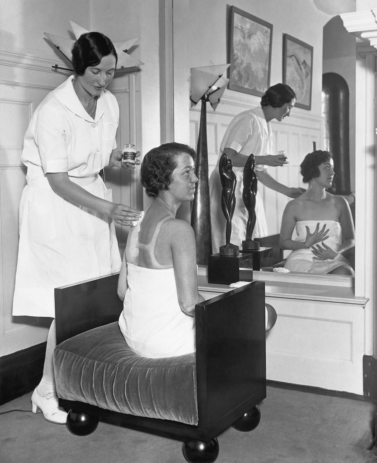 Carolyn Lang applies lotions to Billie Gloss' suntanned back, bleaching it down so that Miss Gloss will be the same pale shade all over.