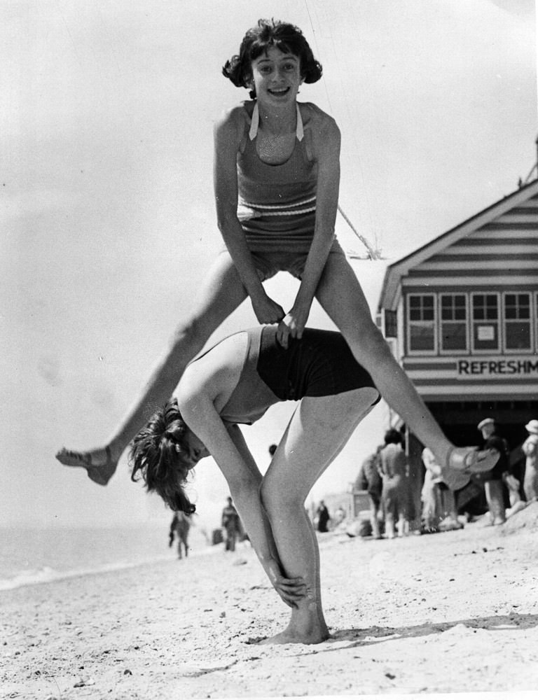 Two girls play leap-frog on the beach at Clacton. 27th June 1936.