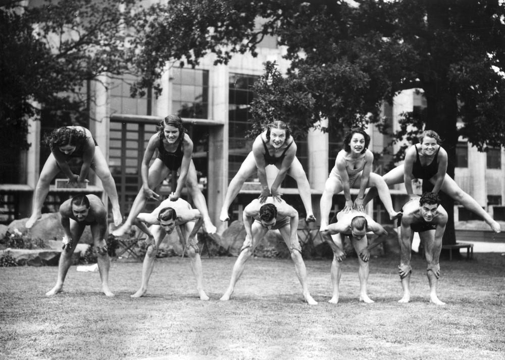 Women divers who are competing in the European Championships at Wembley, London playing leapfrog with the speedway riders as part of a “keep fit” regime. 6th July 1938.