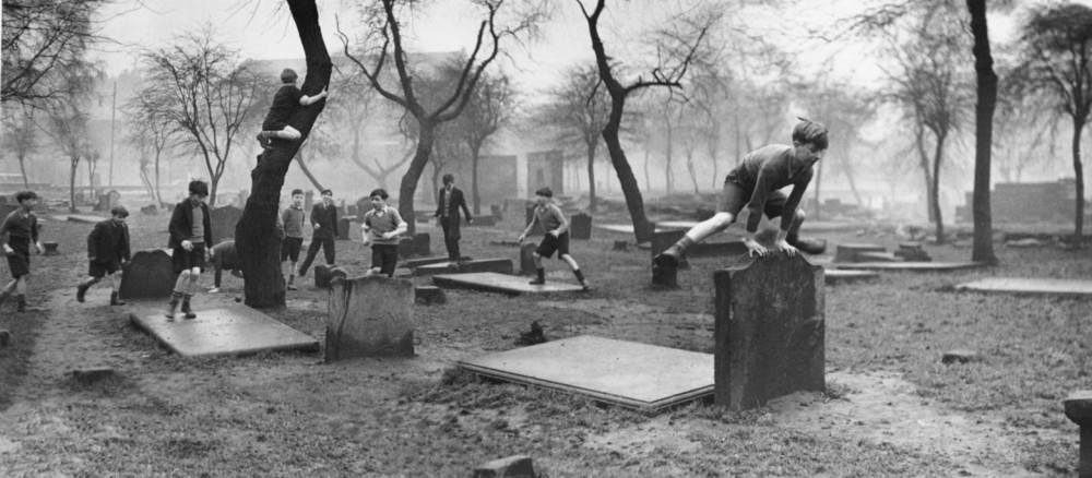 A group of boys from the Gorbals play amongst the gravestones of the Corporation Burial Ground in Rutherglen Road, UK, one of the few areas of greenery in the district, 1948.