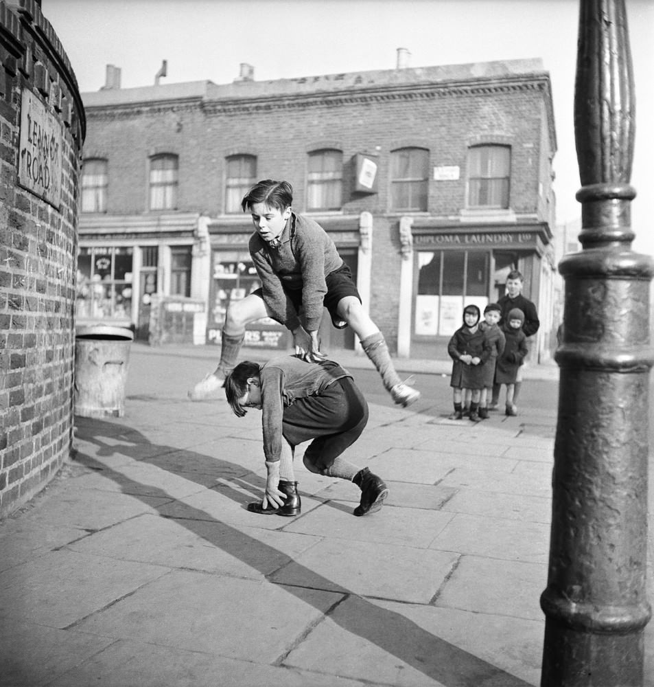 A group of children playing leap frog in the street, 1950.