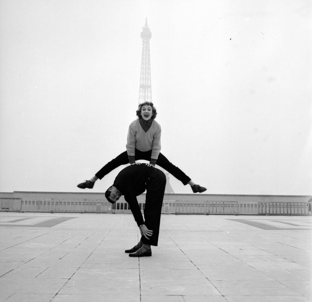 Paris street performers Jean Louis Bert and Grethe Bulow playing leap-frog in front of the Eiffel Tower, 1955.