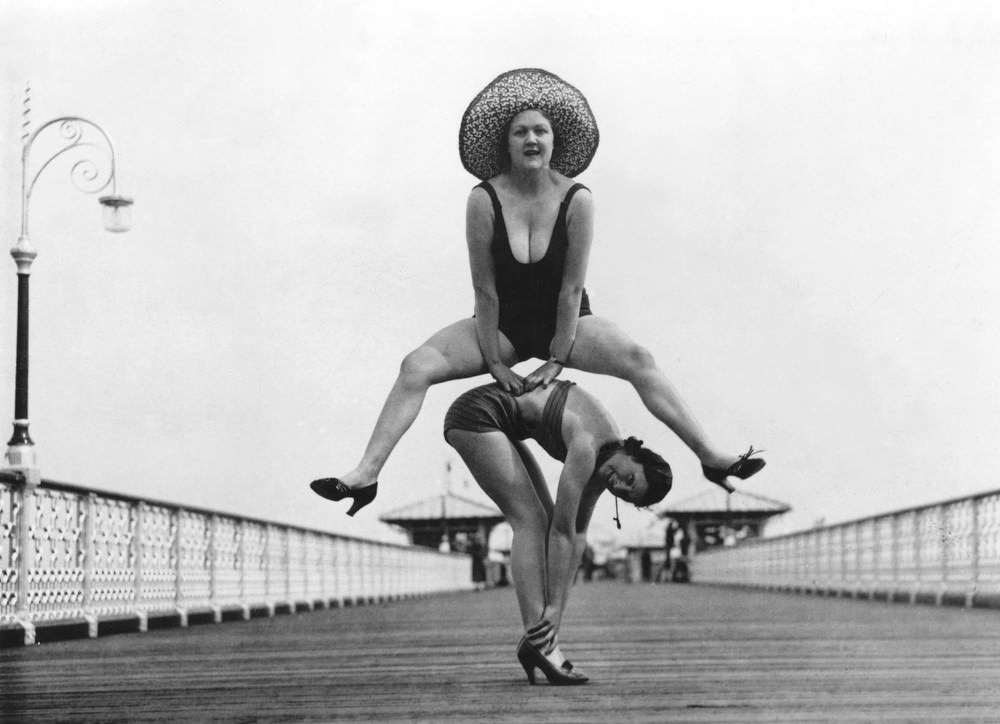 Holidaymakers enjoying a game of leap-frog on the pier at Llandudno. 16th August 1935.