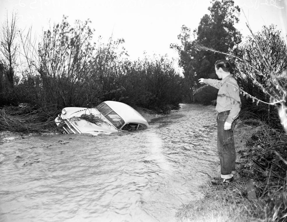 A man point at the drowned car in Mulholland Drive, Los Angeles. 16 January 1952.
