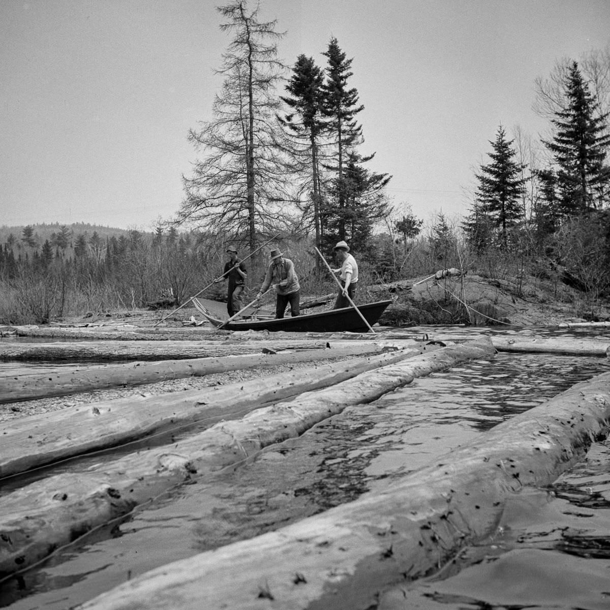 Woodsmen in a "bateau" open up an empty boom.