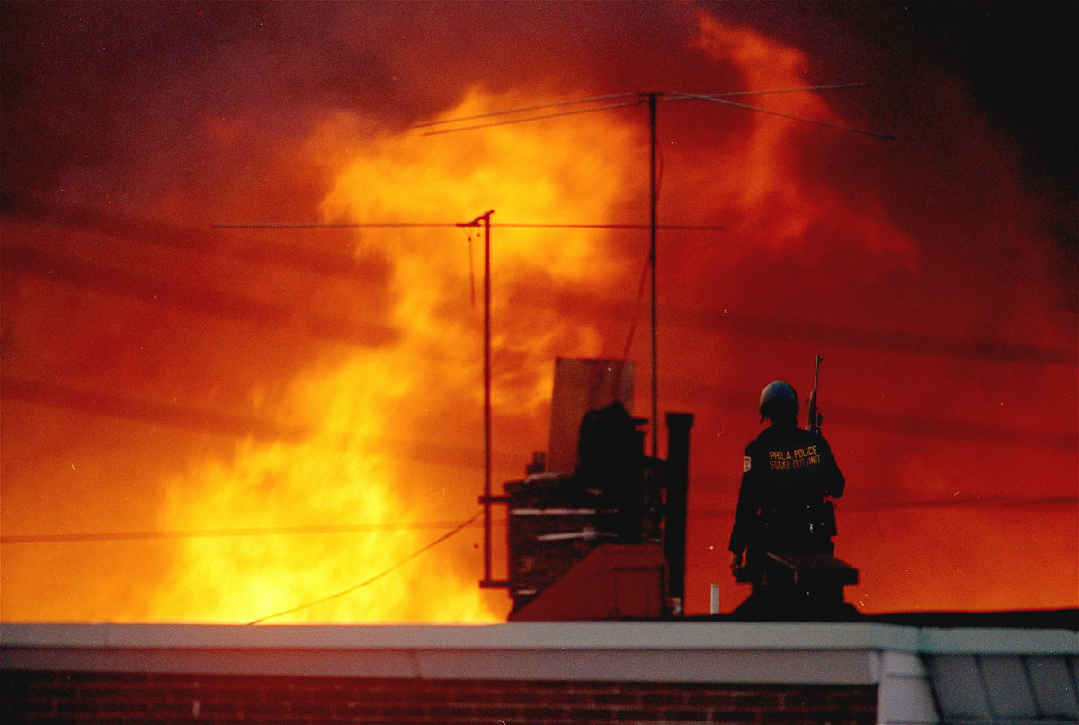 A Philadelphia police officer watches a block of houses burn. May 13, 1985
