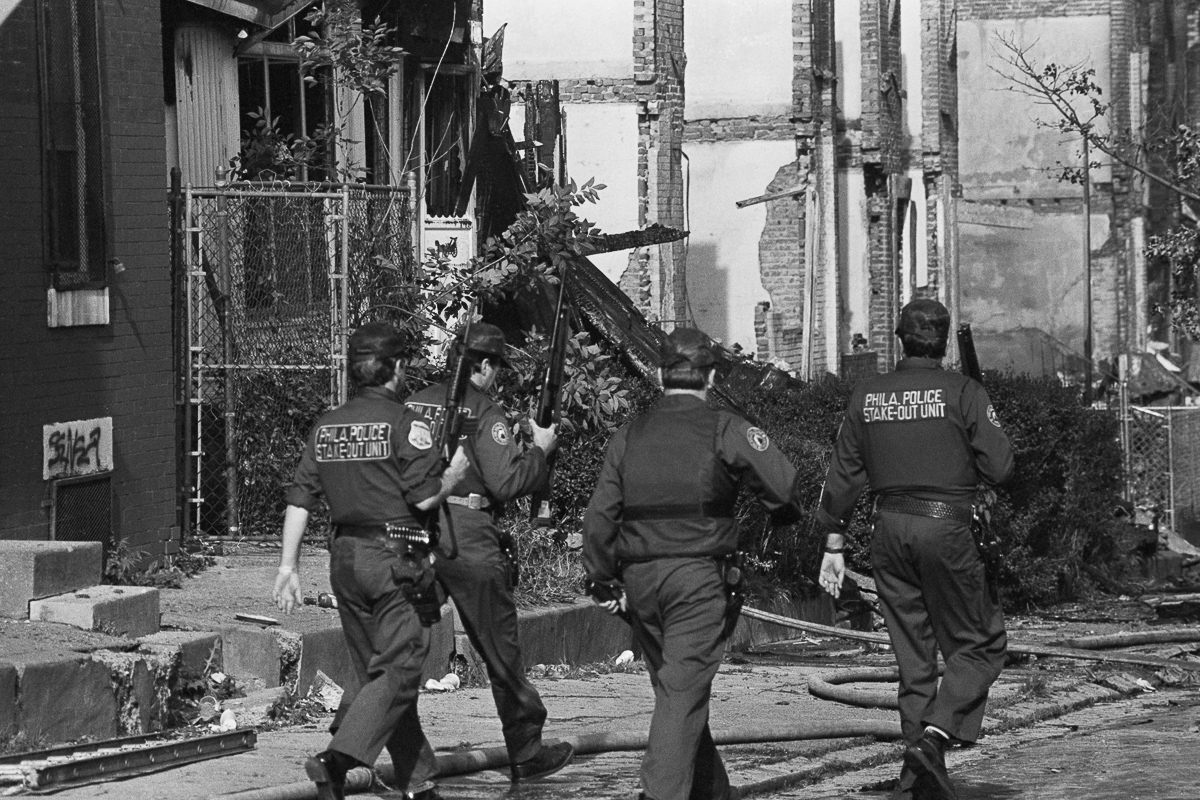 Police officers walk through the destroyed neighborhood the day after the bombing. May 14, 1985