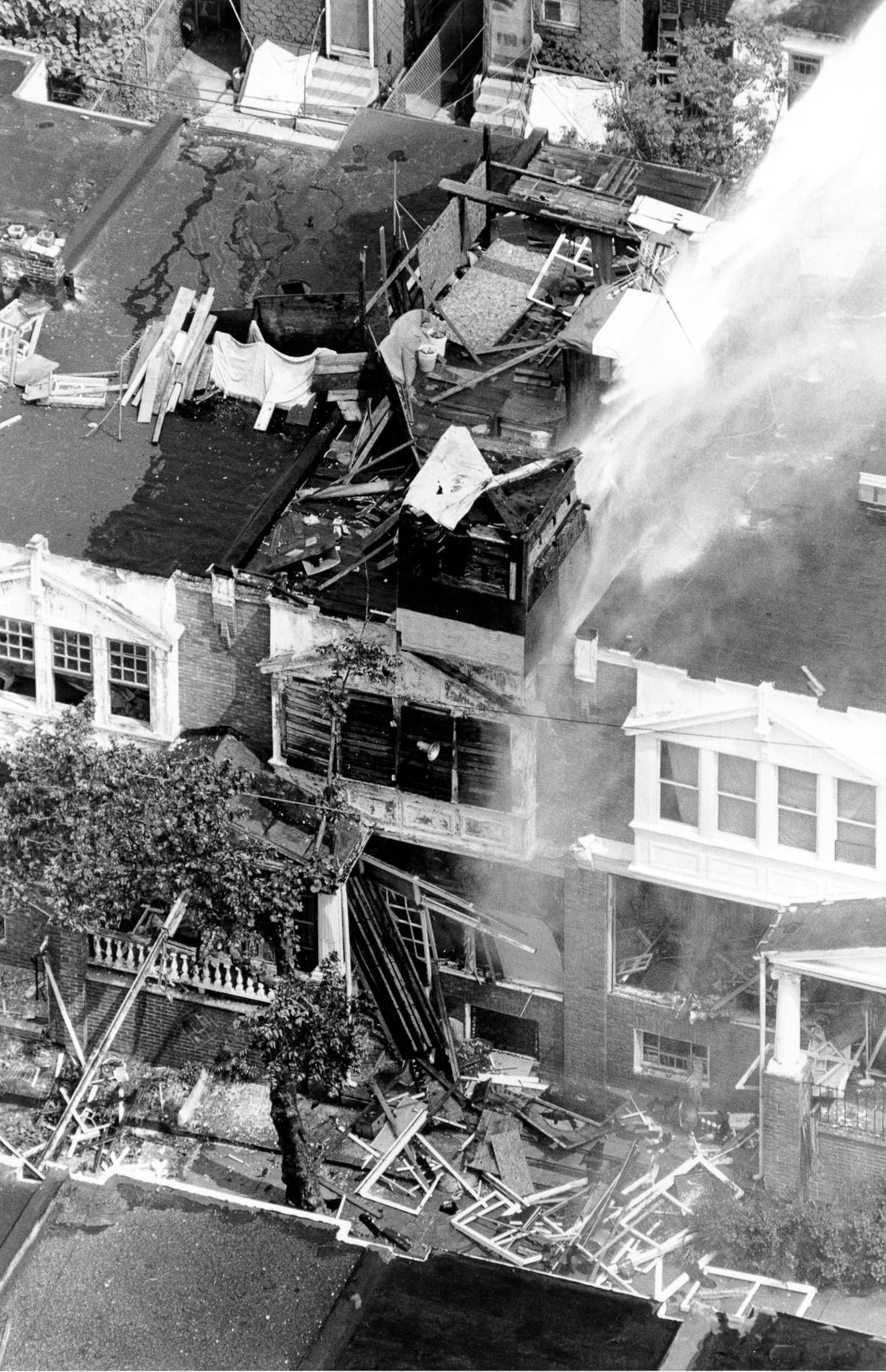 The fortified MOVE headquarters is hit with a deluge of water by firefighters. May 13, 1985