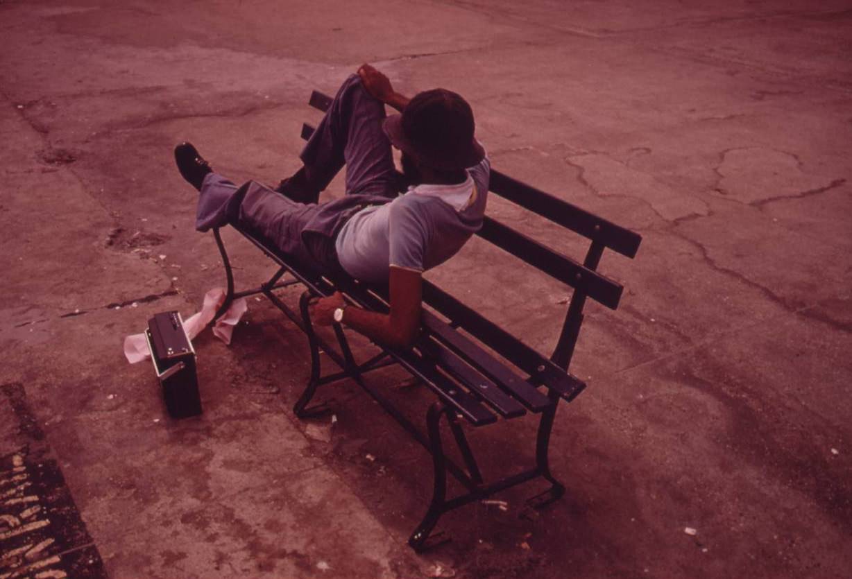 Man lounging on a park bench with his radio on the Reis Park boardwalk in NYC, July 1974.