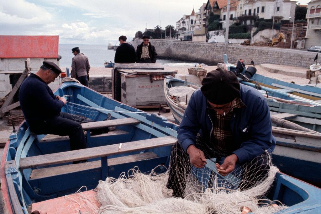 Fishermen stitching up their nets circa 1975 in Portugal.