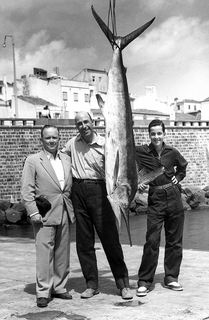 Two men and a boy pose next to a white marlin caught in waters in Portugal circa 1970.