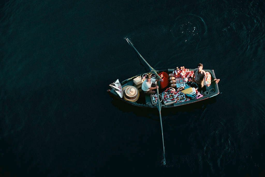 Two men in a bumboat selling souvenirs to tourists in Funchal, Madeira, Portugal, 1970.