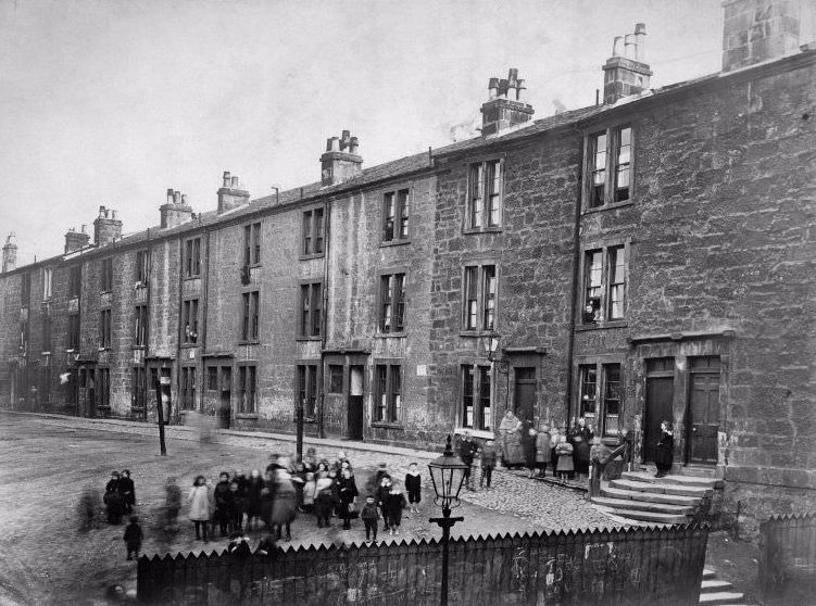 St. James Terrace, Glasgow, with large group of children outside, c.1910. Titled below: ' 3 dwellings, 3 apartments, 24 dwellings, 1 apartment: 2 wash-houses containing in all 29 taps and 8 W.Cs
