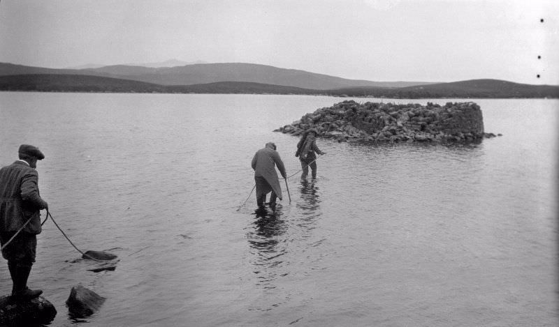 View of RCAHMS surveyors wading out to a dun in 1924, Dun Nighean Righ Lochlainn, North Uist.