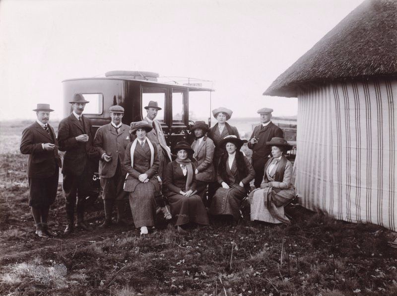 Group photograph showing five men and five ladies beside a large car, outside what appears to be a thatched striped tent. Some of them are members of the Wallace family of Duchal House.