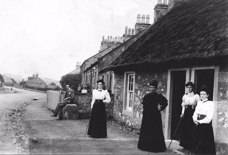 People outside cottages at Troon, South Ayrshire, with thatched cottage in foreground, c.1910.