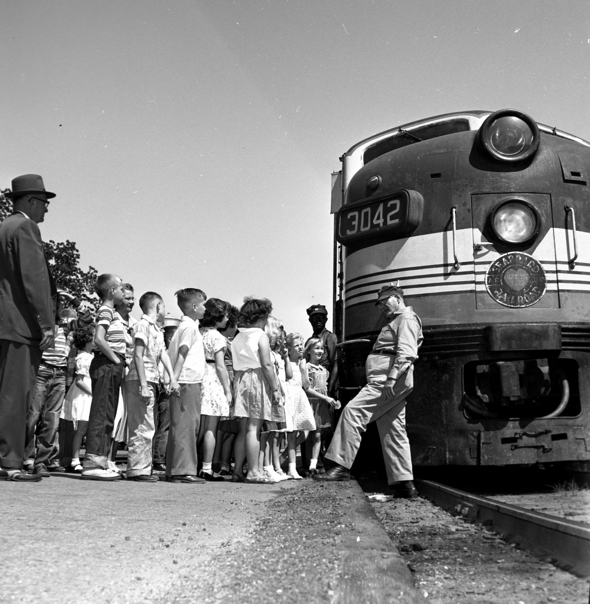 Conductor speaking with children in front of a stopped train – April 25, 1955