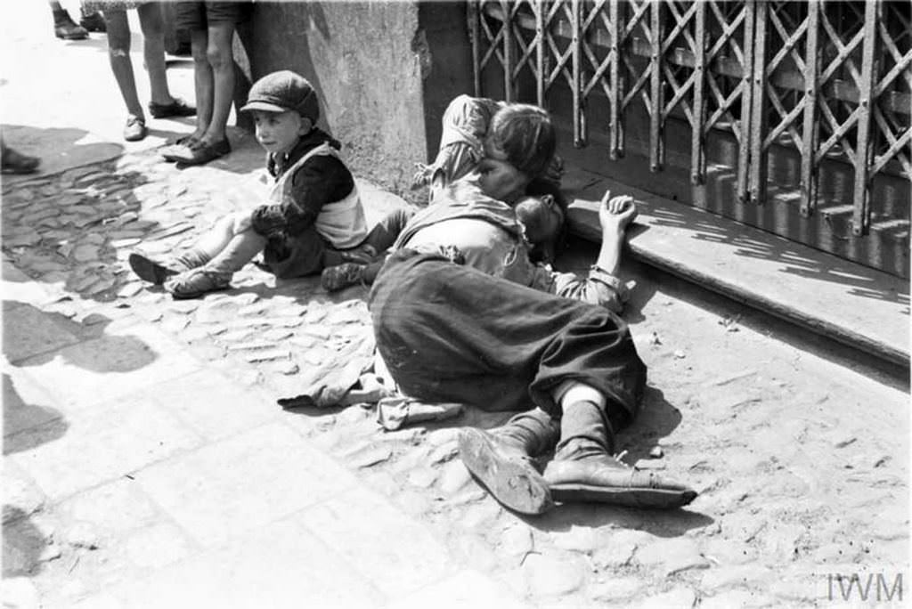A starving man (father ?) and two emaciated children begging on the street in the ghetto.