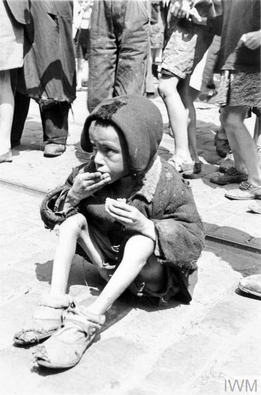 A destitute Jewish child eating a piece of bread in the street of the ghetto.
