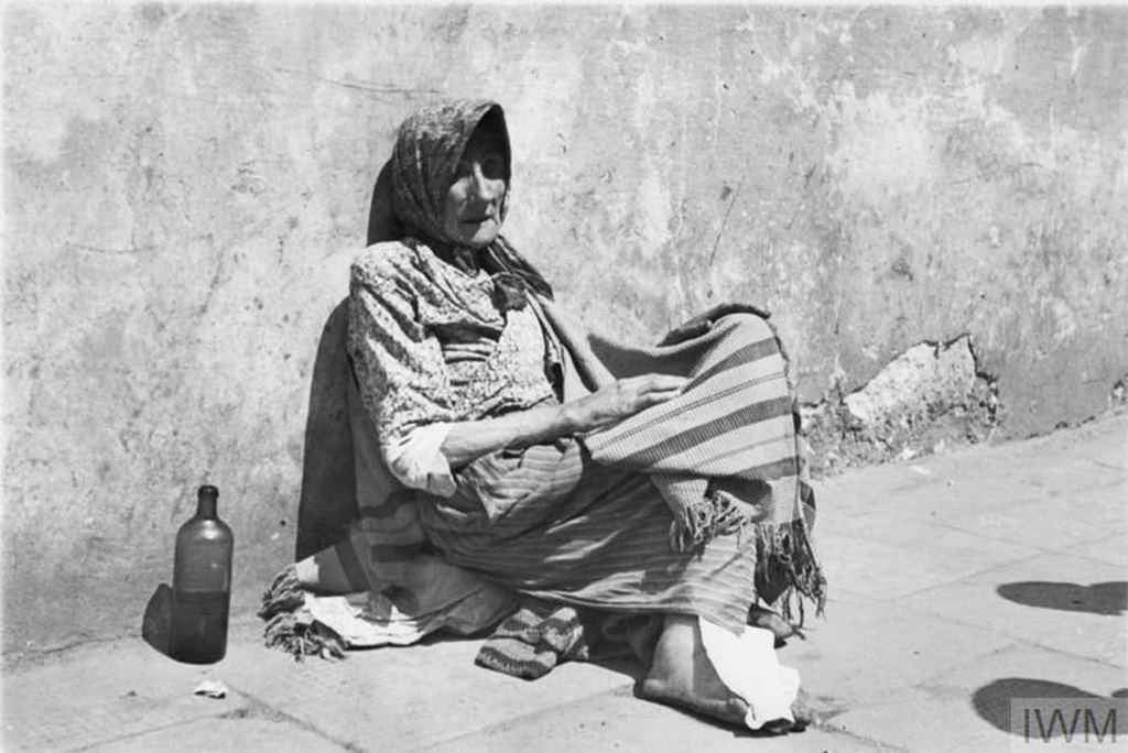 A destitute elderly woman begging in the street.