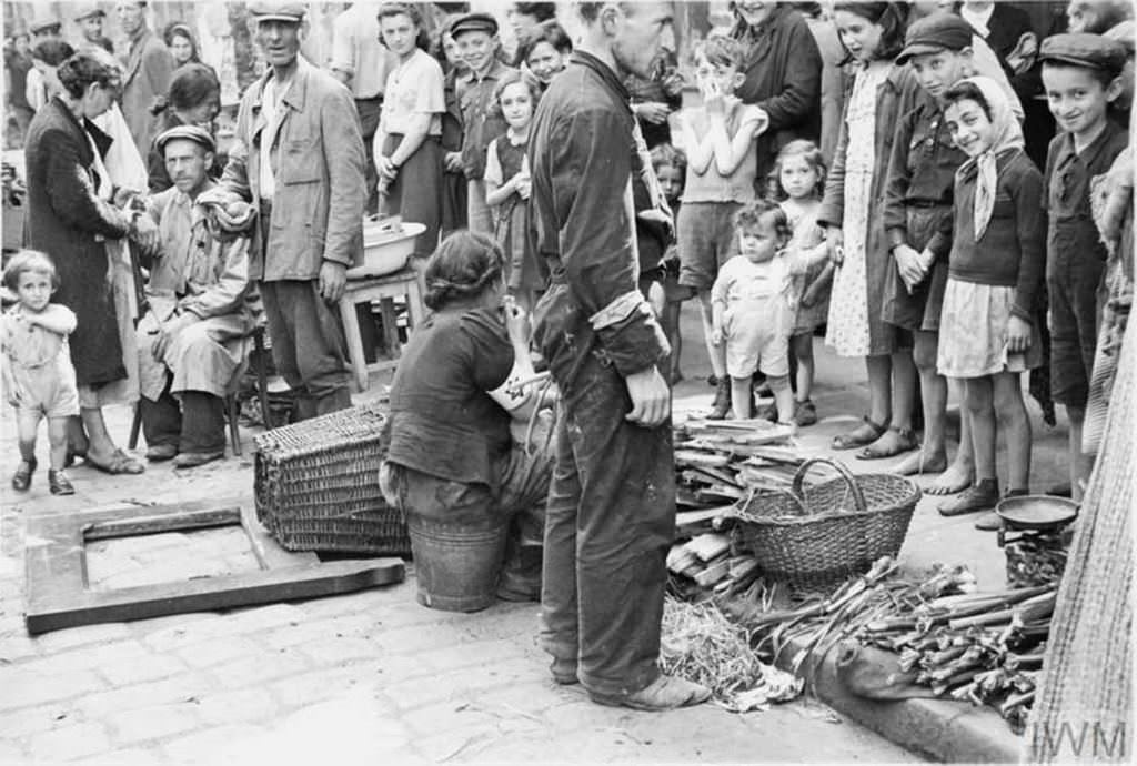 Jewish residents of the ghetto shopping in a vegetable street market.