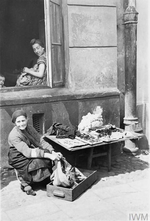 An elderly Jewish woman selling her scarce possessions in the street of the ghetto.