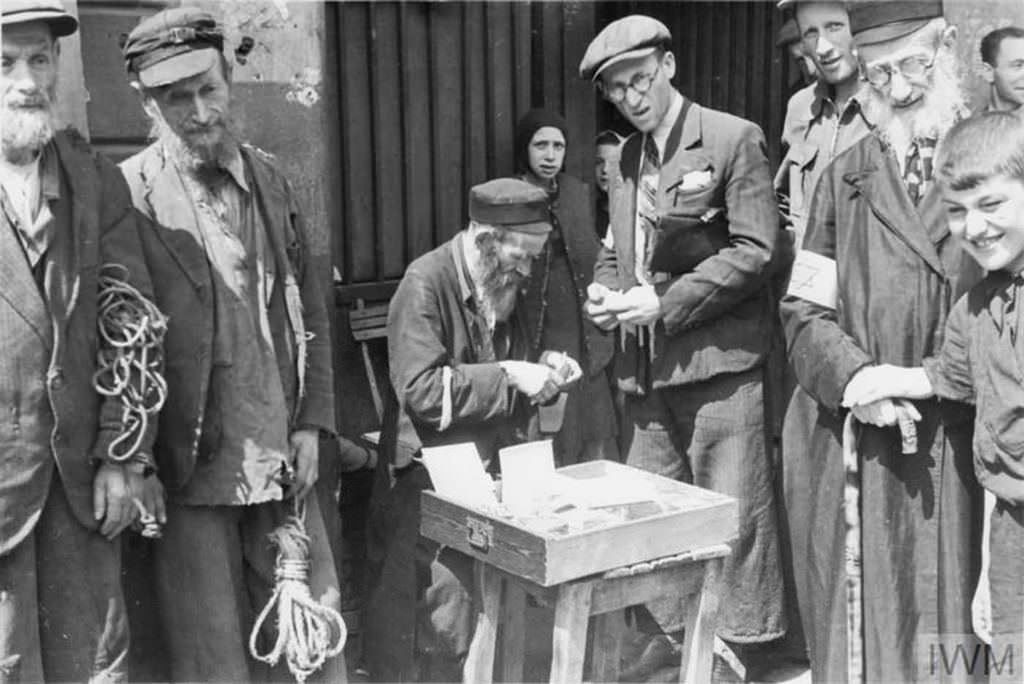 An armband seller making a transaction in the street. Two elderly men on the left trying to sell pieces of rope – almost anything could be a subject of trade to earn money for food.