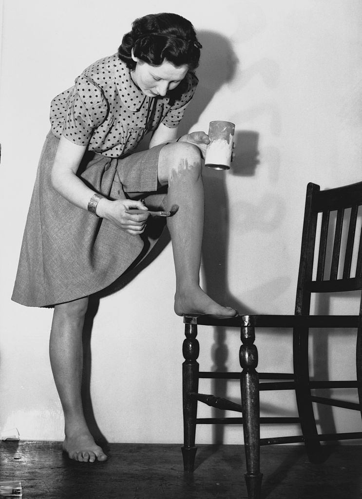 A woman in the United Kingdom paints her legs with dark paint so that it appears as though she is wearing stockings.