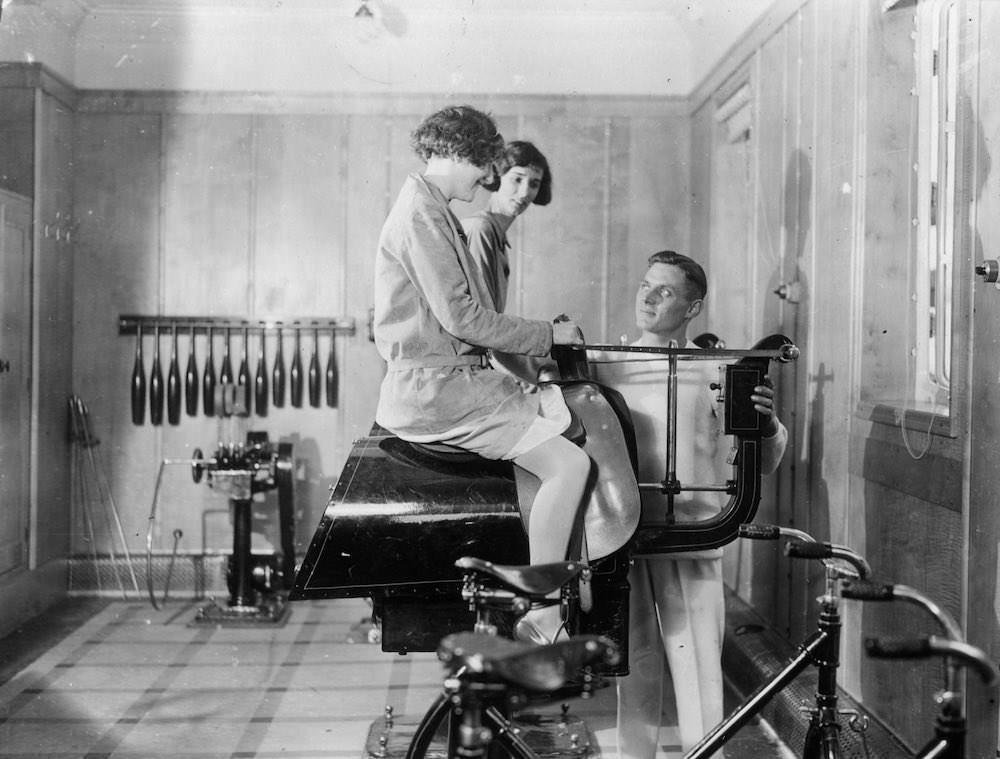 Passengers on the Canadian Pacific liner Duchess of Bedford keep fit in the ship's gymnasium, with the help of a riding machine. 1931