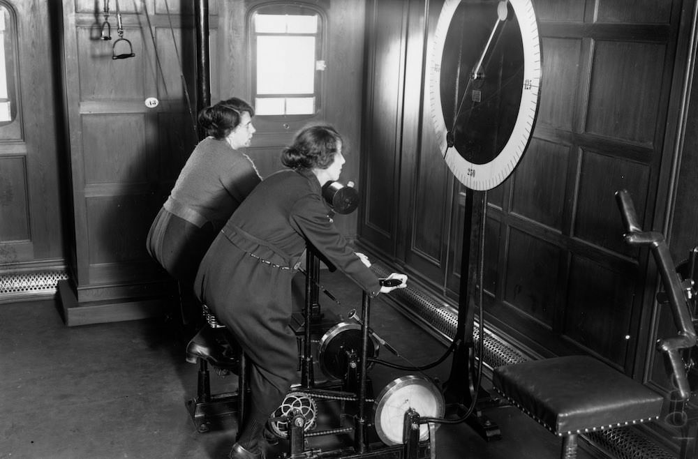 Two women using the cycle machine in the gym on board the Homeric Liner, taken over from the Germans by White Star. 1922