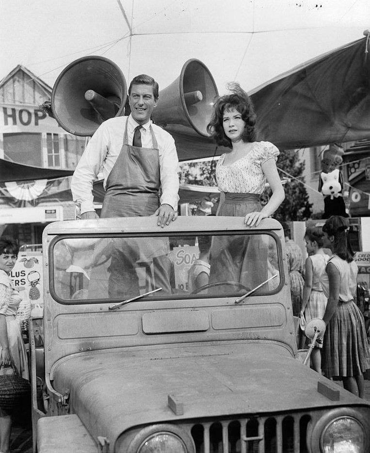 Dick Van Dyke and Shirley MacLaine standing up in a jeep in a scene from the film 'What A Way To Go', 1964.