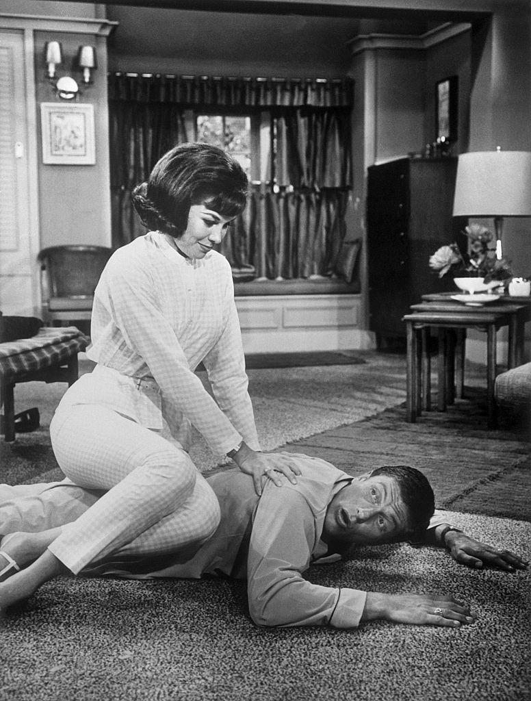 Mary Tyler Moore Sitting on Dick Van Dyke's back, as he lies on the floor.