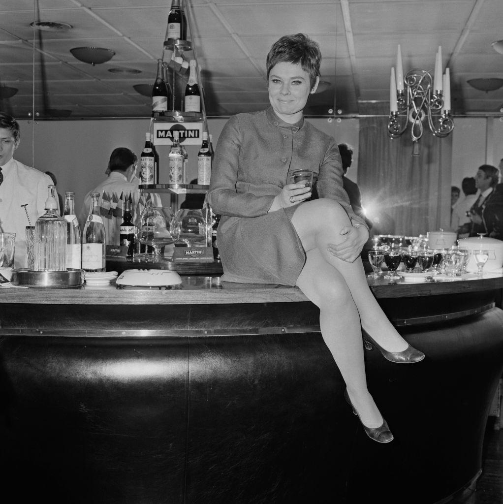 Judi Dench sitting on a bar counter, UK, 9th April 1968.