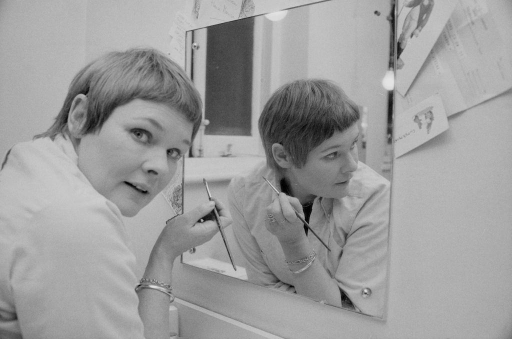 Judi Dench doing her makeup in front of a mirror, 1975.