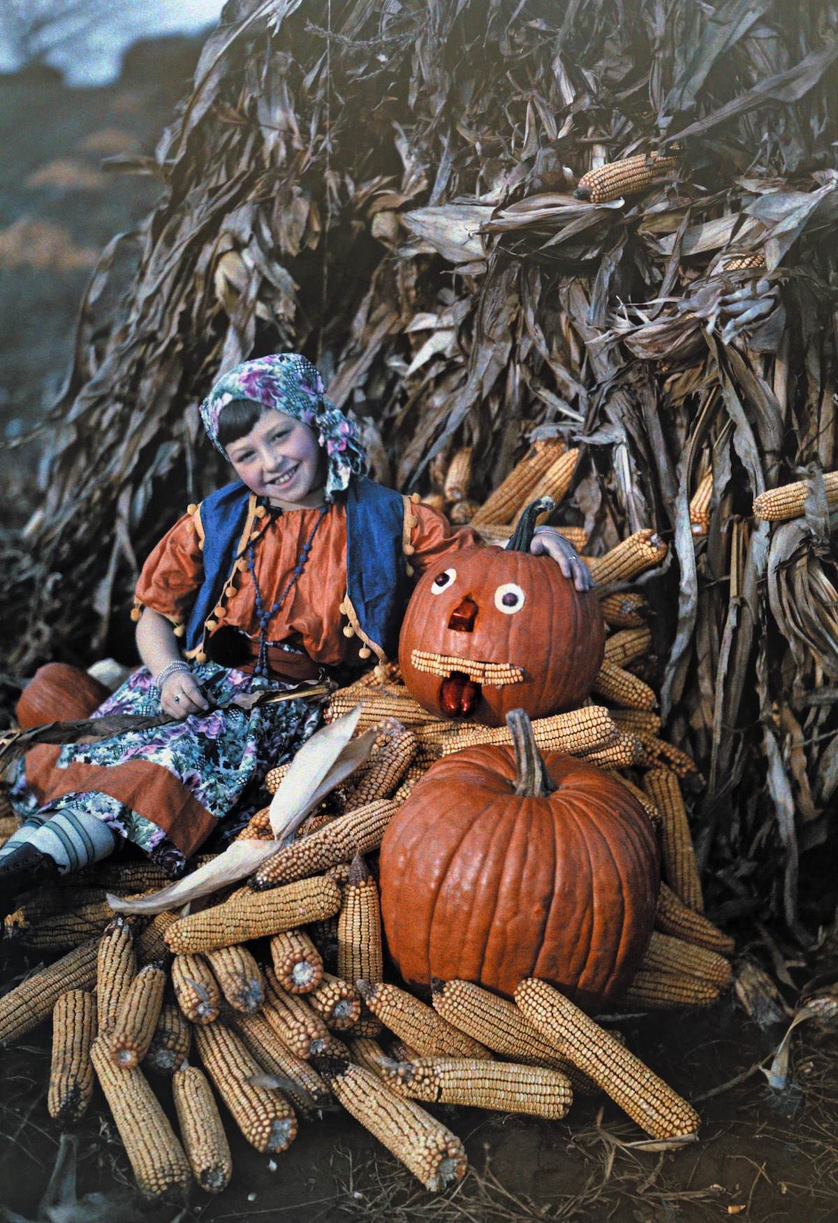 A girl poses with corncobs and pumpkins during the harvest, Virginia.