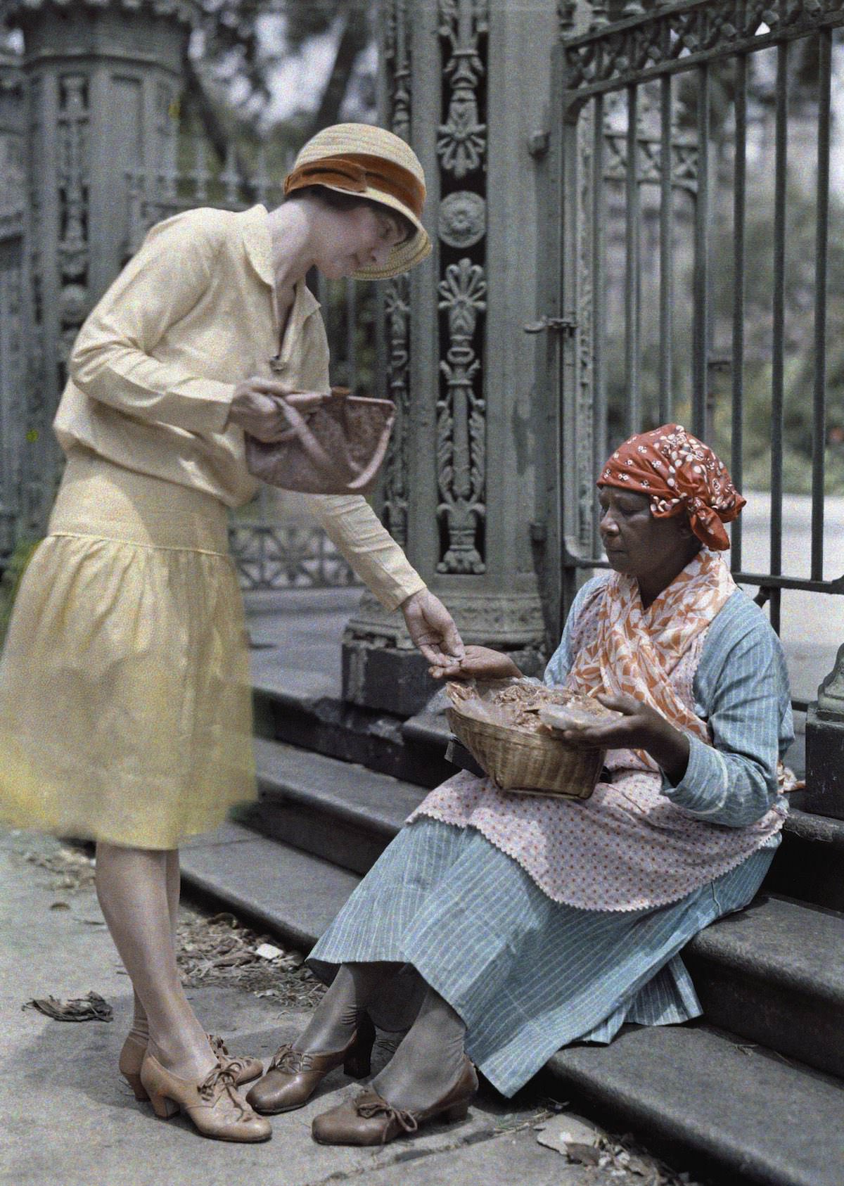 A woman sitting on stone steps in the French Quarter sells pralines.