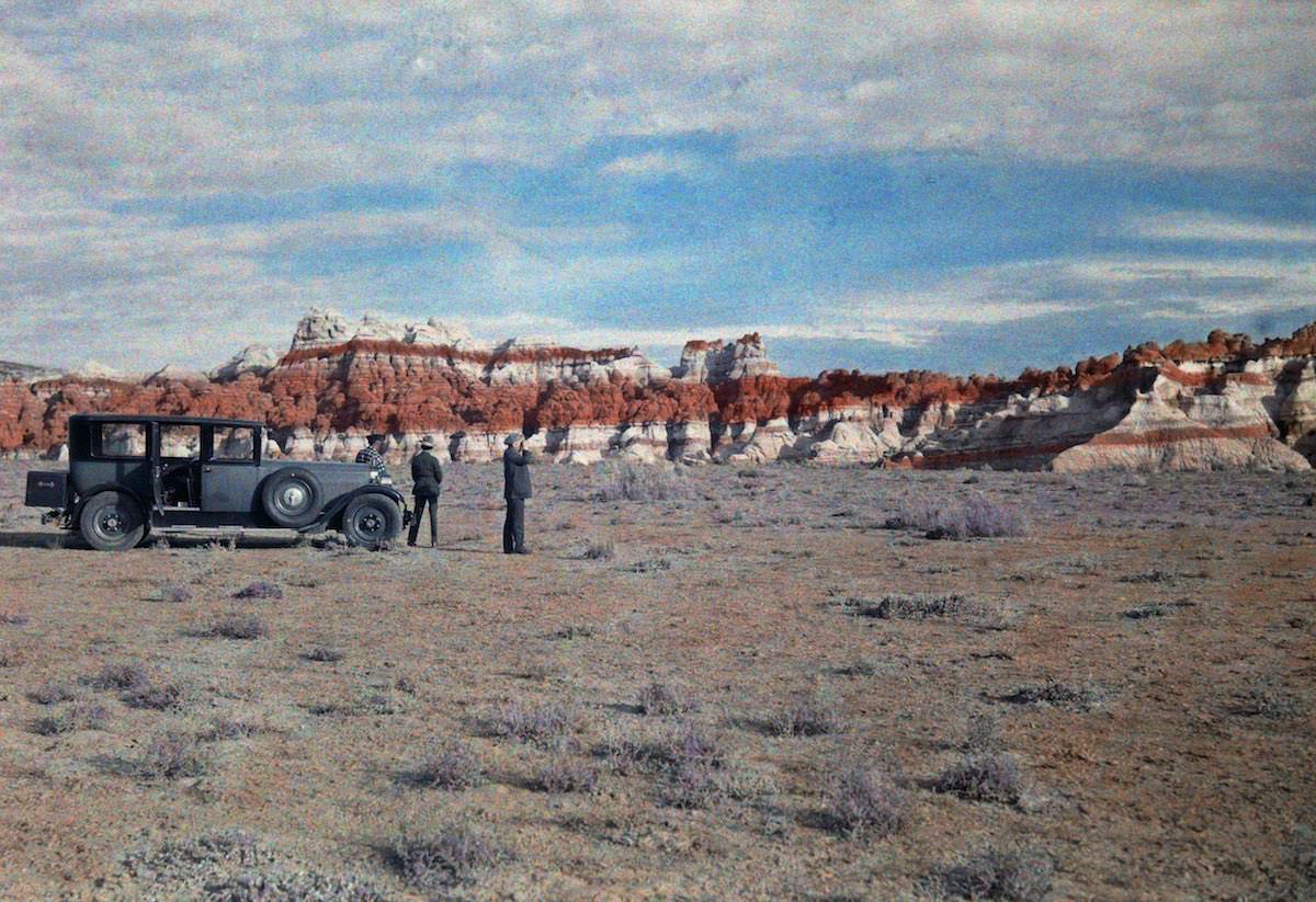 Men stand next to a car in a field and look at a nearby canyon. Hopi Indian Reservation