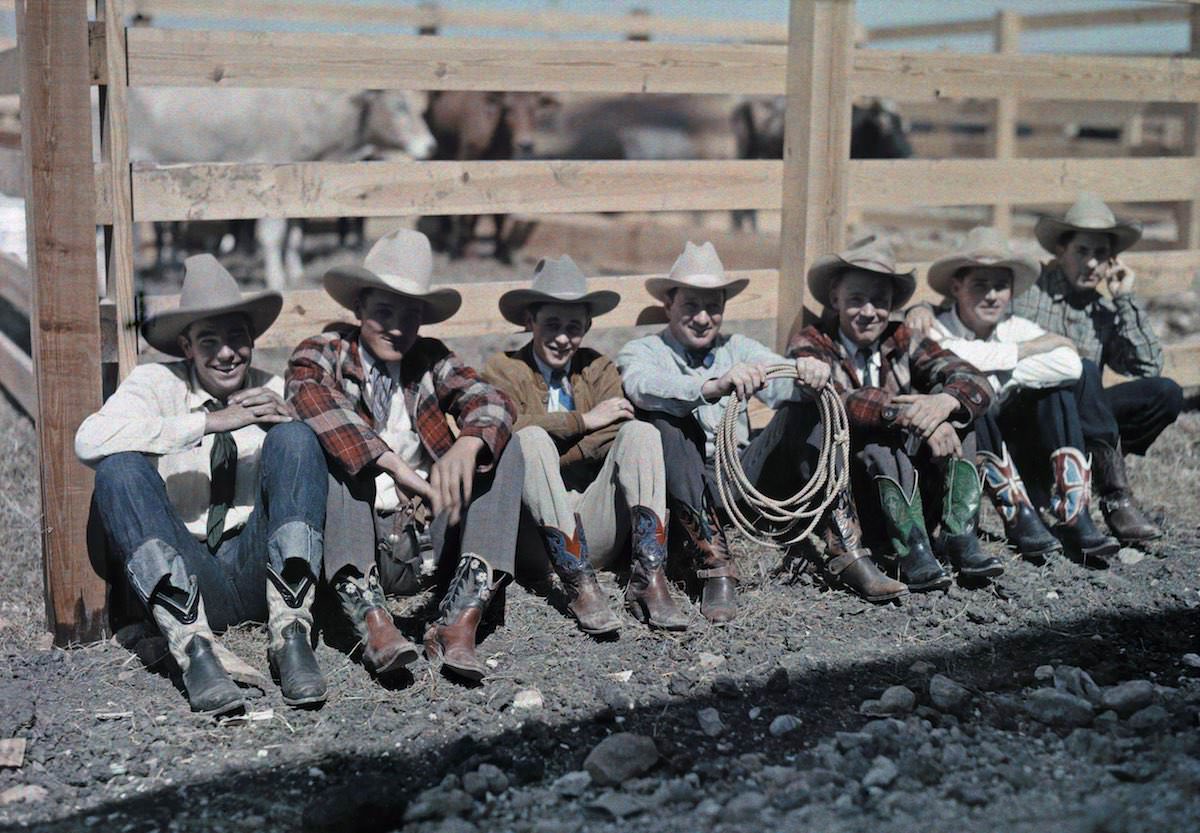 Cowboys and horseback riders sit along a fence at a rodeo, San Antonio, Texas.