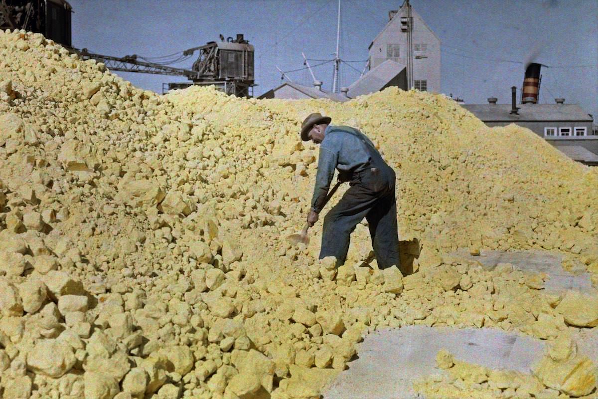 A man shovels sulfur in a warehouse near the pier, Galveston, Texas.