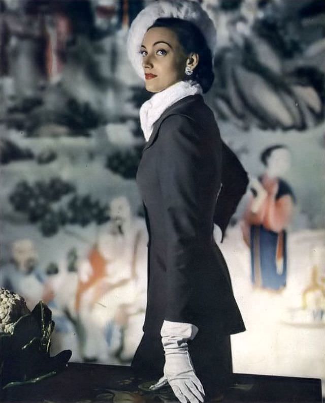 Model in all-day suit of gray Miron worsted broadcloth with longer jacket by Larry Aldrich, dressed up with ermine ascot and beret, 1947