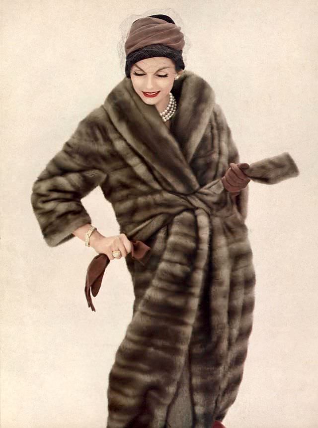 Anne St. Marie is wearing belted mink fur coat with Verdura pearl necklace and hat, October 1958
