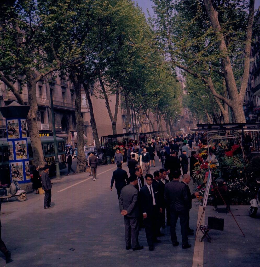 View of a street scene with florist stalls and a street artist in Barcelona, 1966.