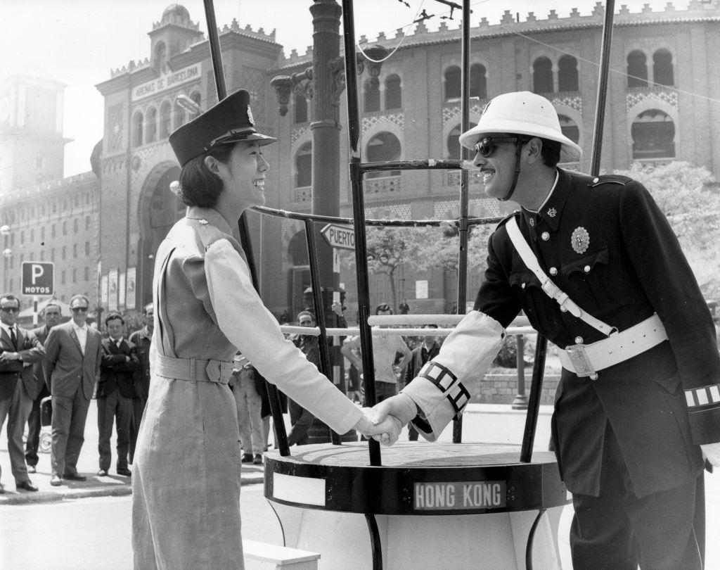 A policewoman from Hong Kong shakes hands with a Spanish policeman at the International Samples Fair in Barcelona, 1966.