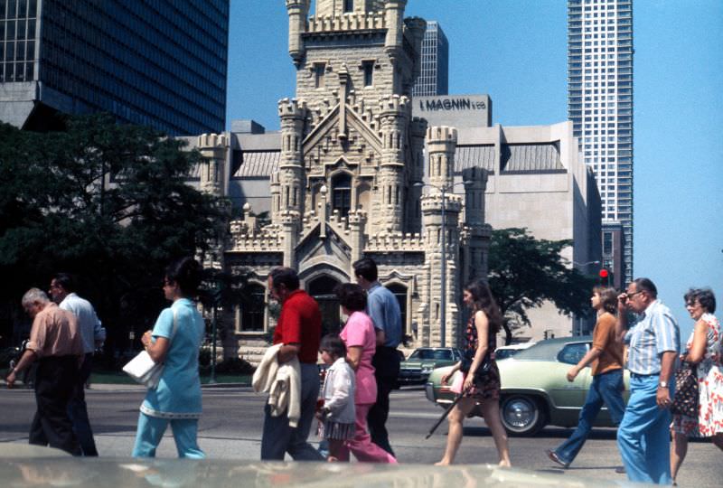 Pedestrians crossing North Michigan Avenue at the intersection with East Chicago Avenue, in front of the Chicago Water Tower, 1976