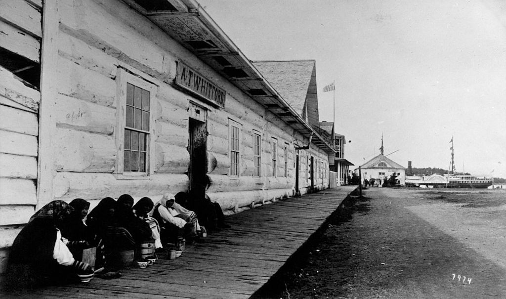 Crowd huddled next to building in Sitka, Alaska, circa 1890.