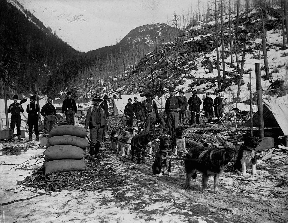 Prospectors pose with a dog sled team at an issolated camp in Yukon Territory near Dyea Canyon, Alaska, 1897.