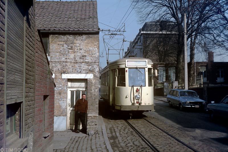 A miner (or probably a steel worker) enjoys the winter sun as a vicinal tram passes his home in. Dampremy, 1973