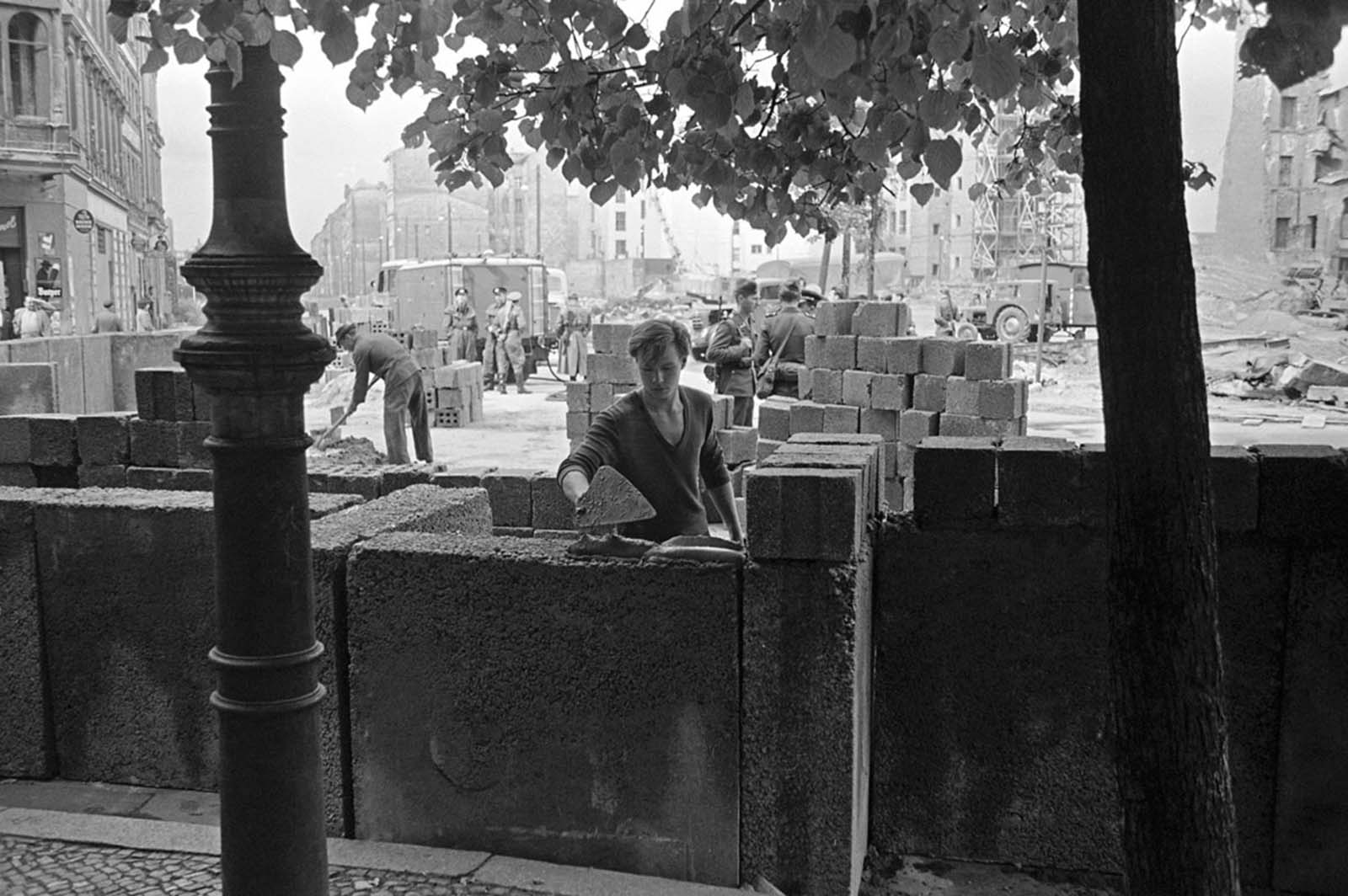 A young East Berliner works on a concrete wall that was later topped by barbed wire at a sector border in the divided city on August 18, 1961.
