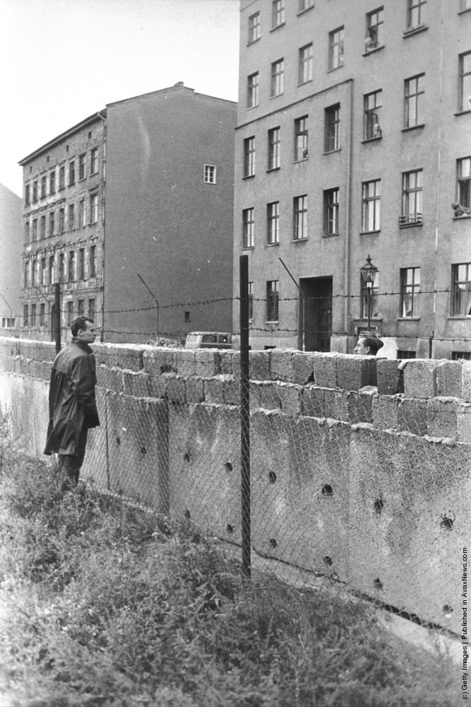 A citizen of East Berlin peers through barbed wire at a West Berliner over the Berlin Wall, Berlin, Germany, 1960s.