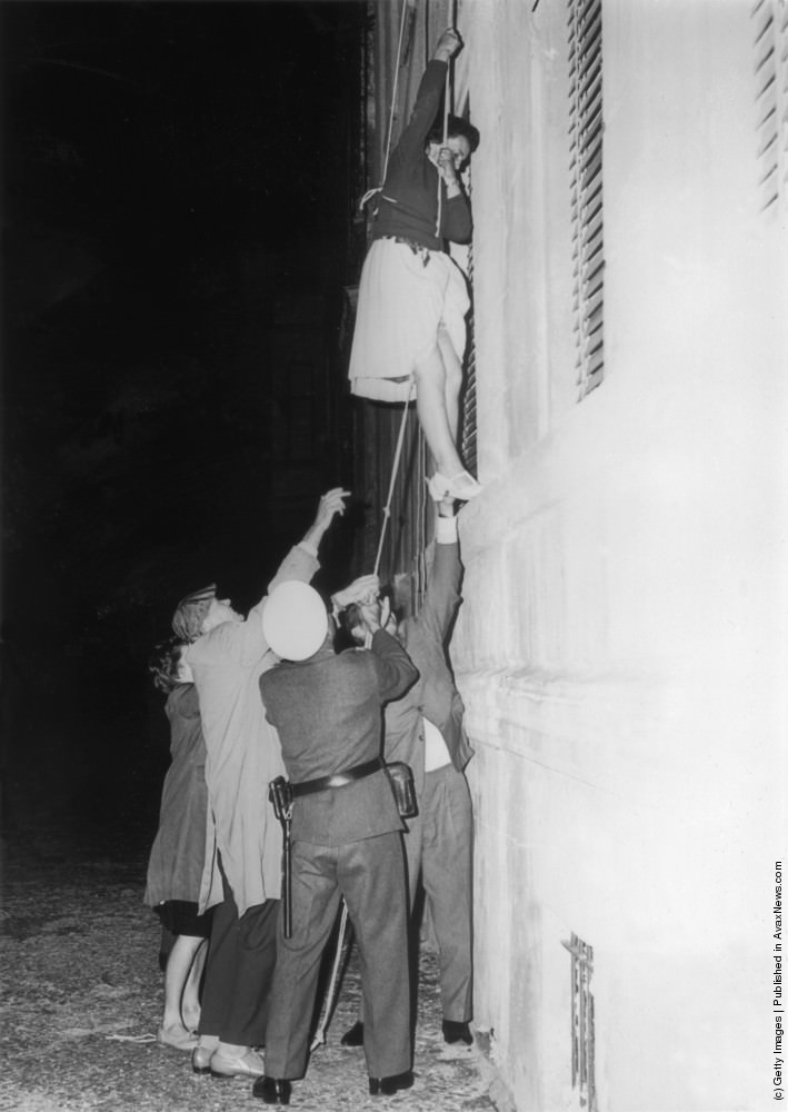 A woman is lowered from a window in Bernauer Strasse on a rope to escape into the western sector of Berlin after the post-war division of the city, 10th September 1961.